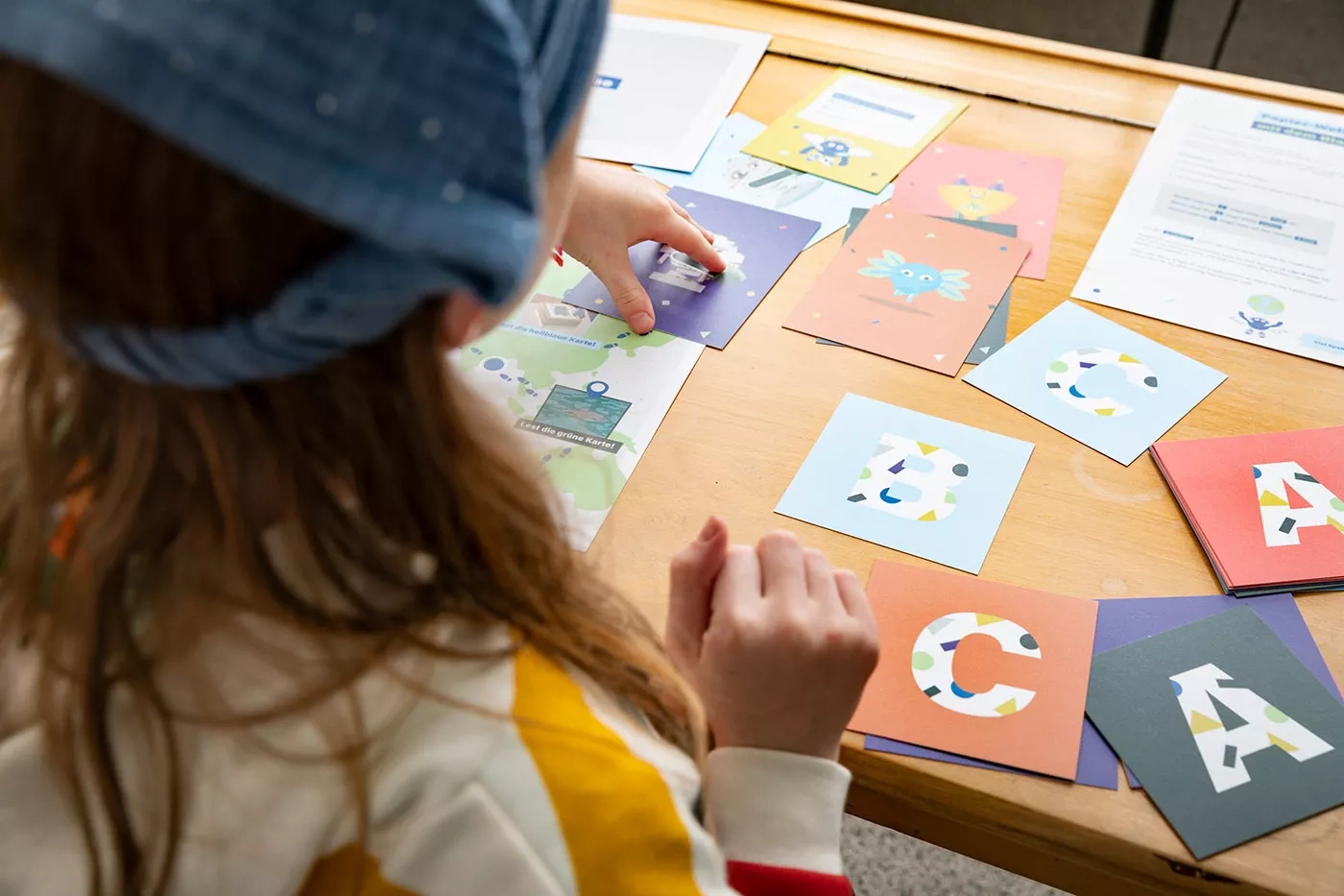 Kind schaut sich Spielkarten mit Buchstaben aus der Schulbox an