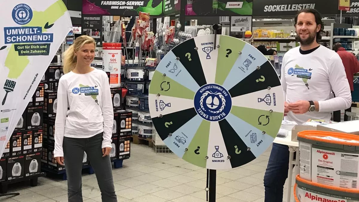 A Blue Angel employee stands in front of a wheel of fortune at the Toom store