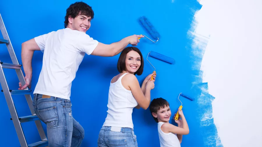 Mann, Frau und Kind streichen gemeinsam eine Wand blau ©iStock/ValuaVitaly