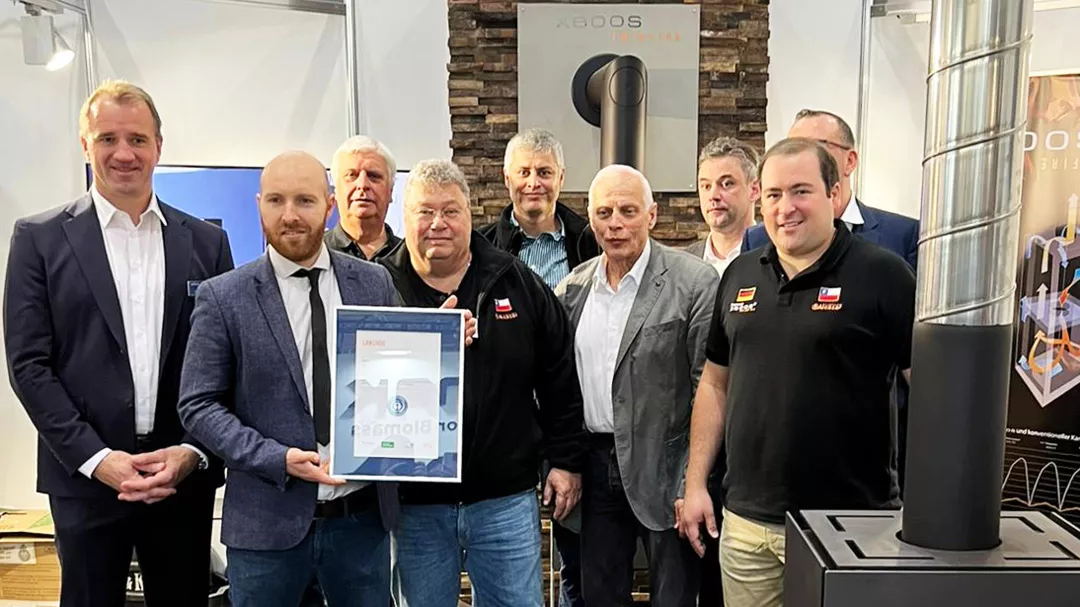 Nine men stand together smiling and one holds the framed certificate 