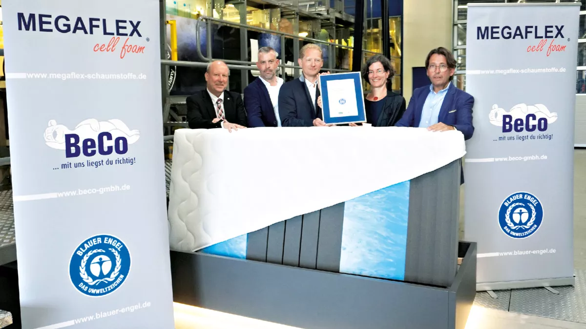 Four men and one woman hold up their certificate behind a mattress