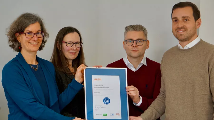 Zwei Frauen und zwei Männer halten ein Bild mit der Urkunde hoch