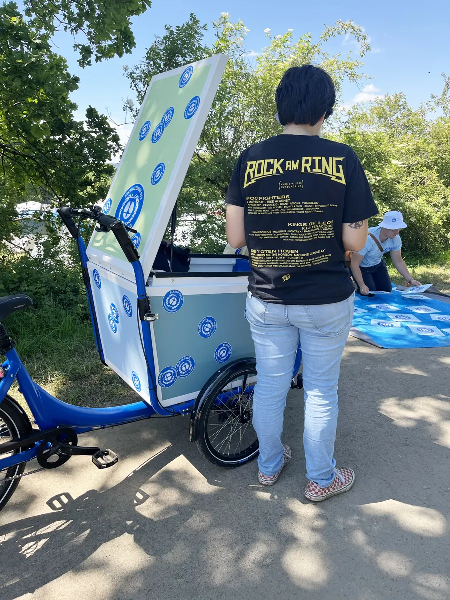 Person with Rock am Ring T-shirt next to the Blue Angel cargo bike