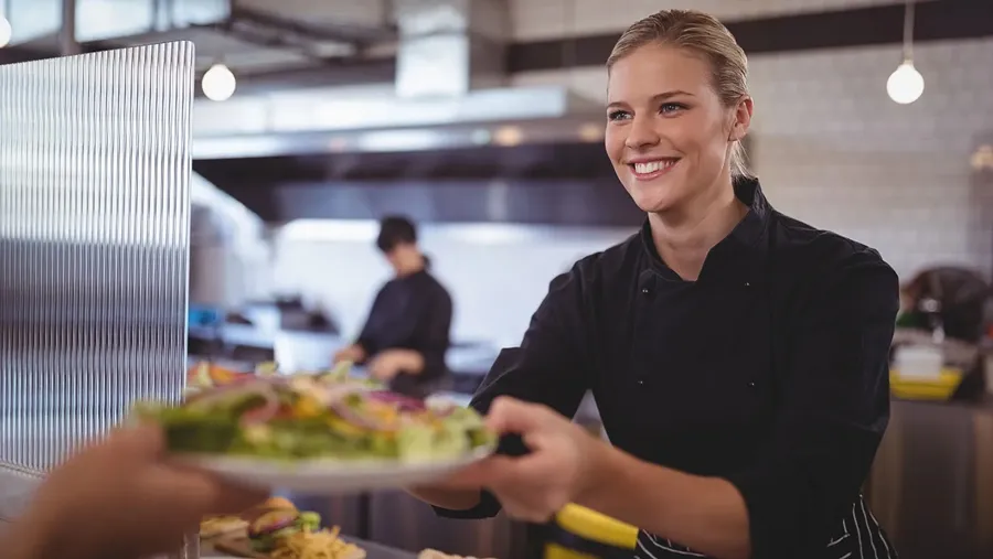 Frau reicht Essen aus der Küche