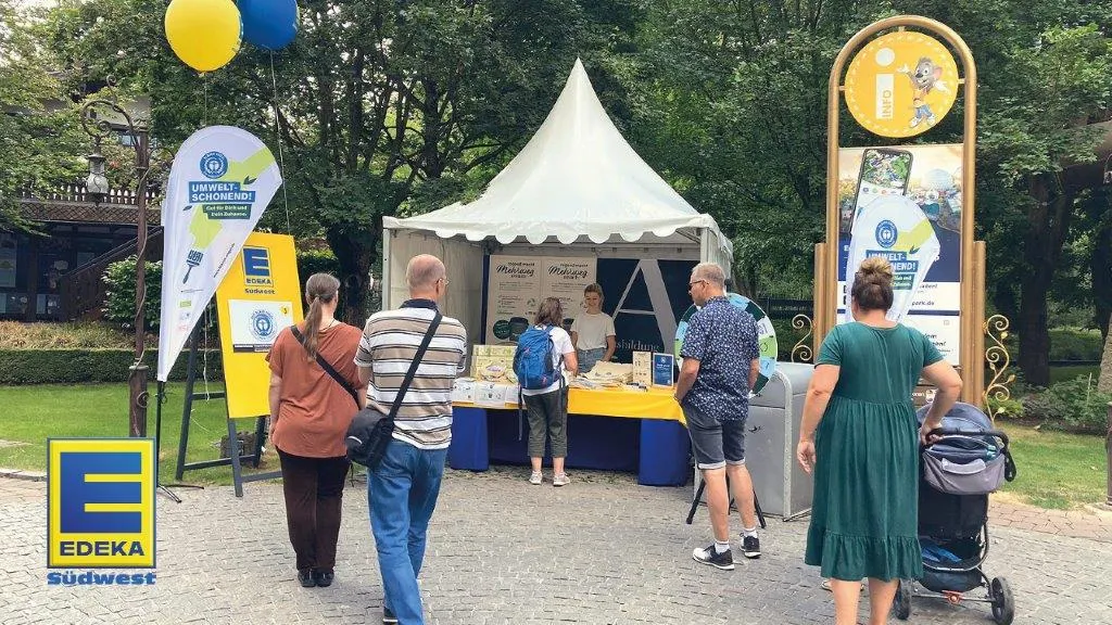 Edeka Südwest with a Blue Angel campaign stand in the park with stands and an audience