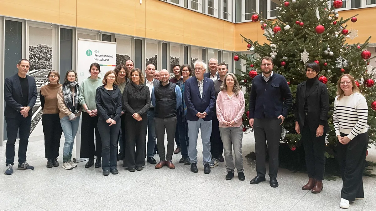 Gruppenfoto mit verschiedenen Personen vor einem großen geschmückten Weihnachtsbaum